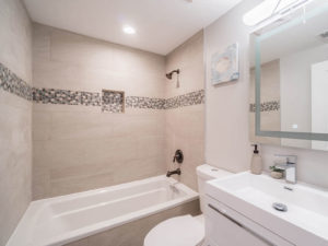 Clean, sleek bathroom with bath tub-shower combination, vanity, and a toilet