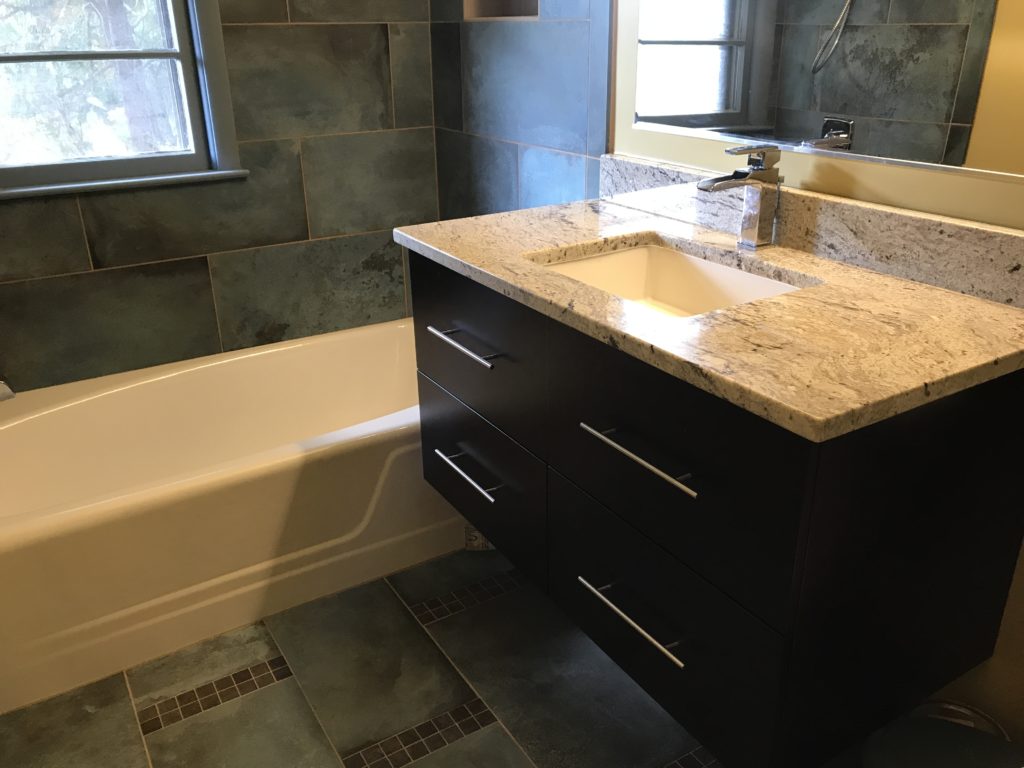 Dark bathroom with floating dark brown vanity and a bath tub