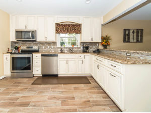 L type kitchen with white cabinets, granite countertop, and tiles flooring