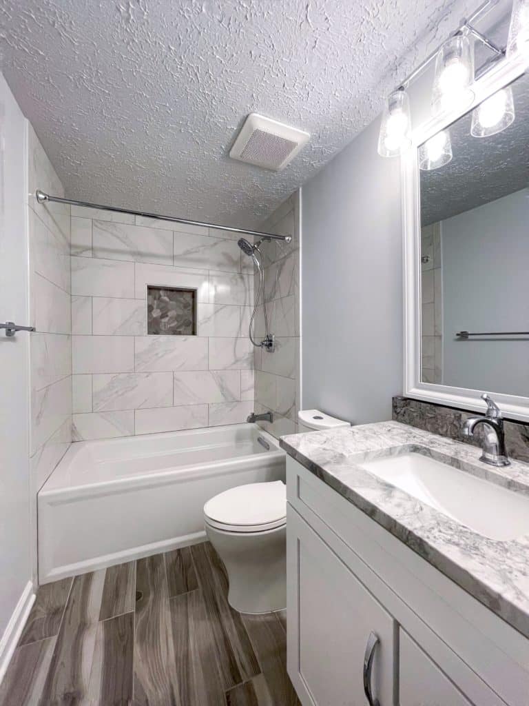 Classy bathroom style with wood flooring, bath tub, vanity, and a toilet