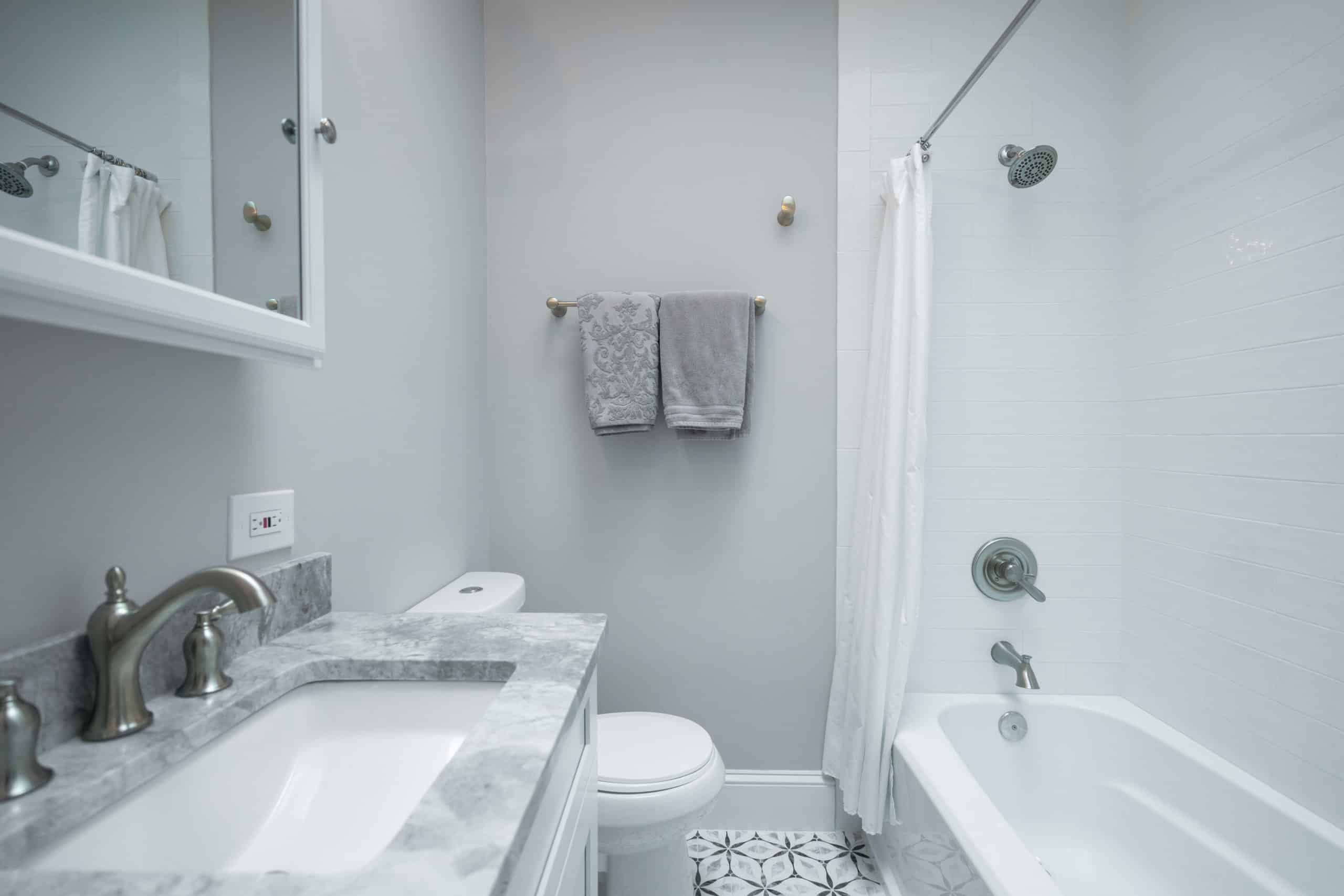 Grey bathroom with white shaker vanity, toilet and a tub-shower combination