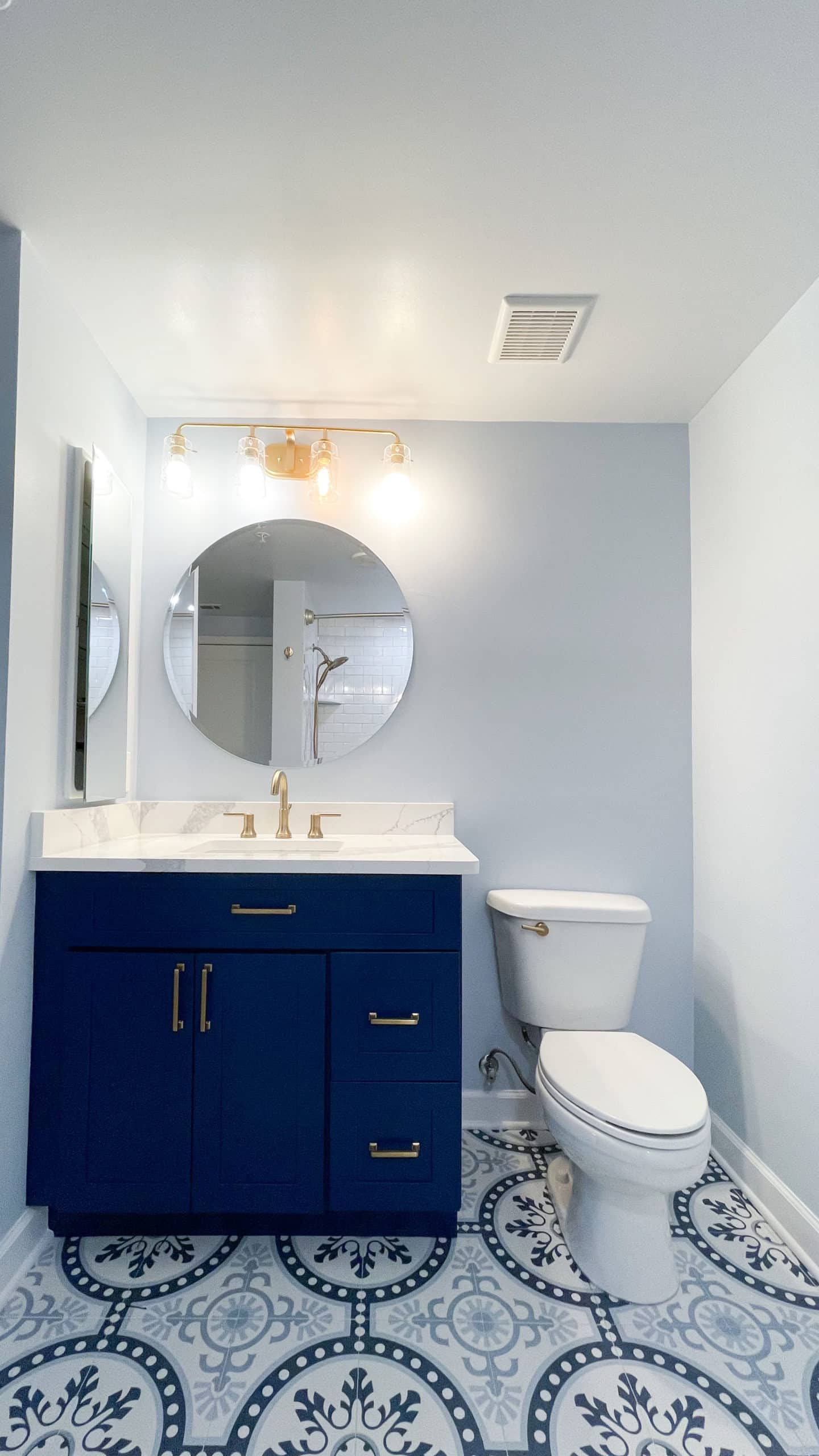 Light blue bathroom with navy blue vanity and a toilet
