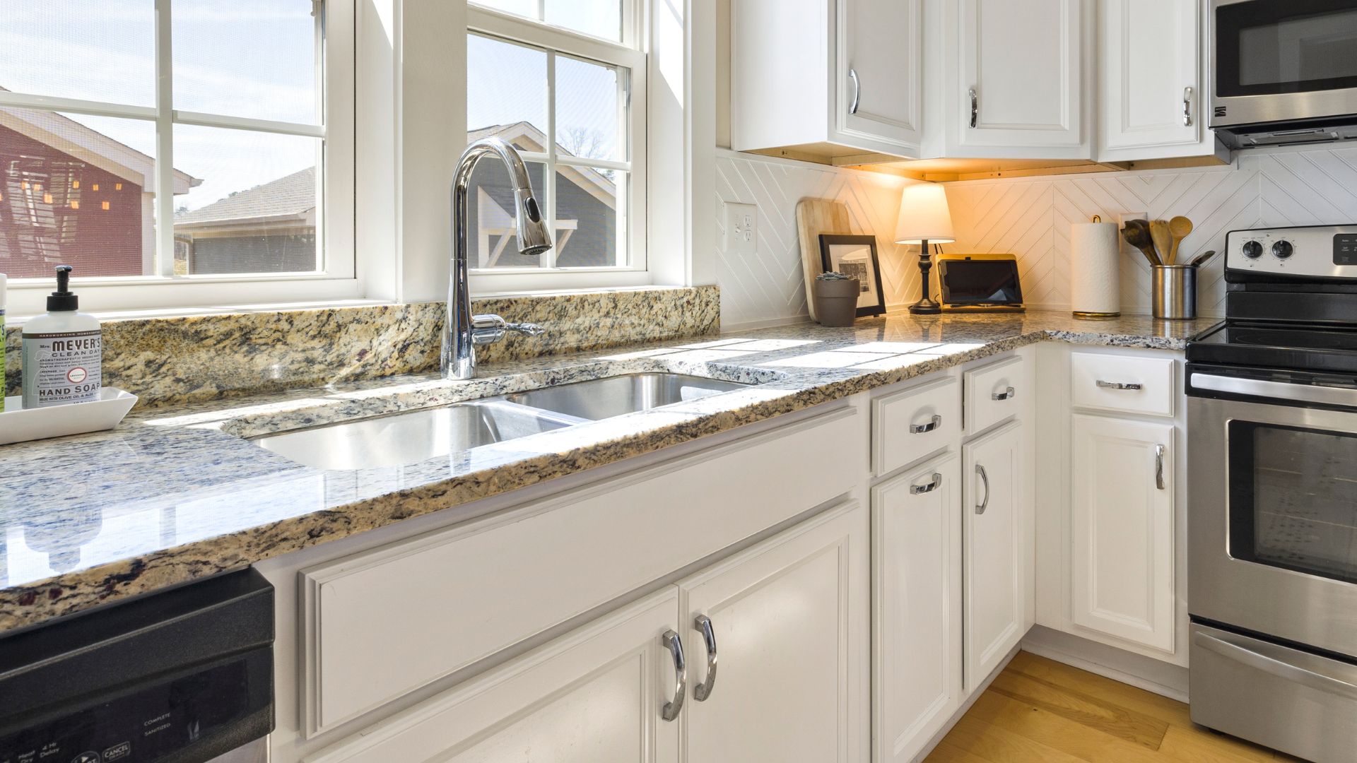 Small transitional L-type kitchen with white cabinets, and granite countertops