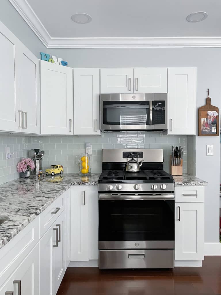 Bright white kitchen design with white shaker cabinets and grey countertops