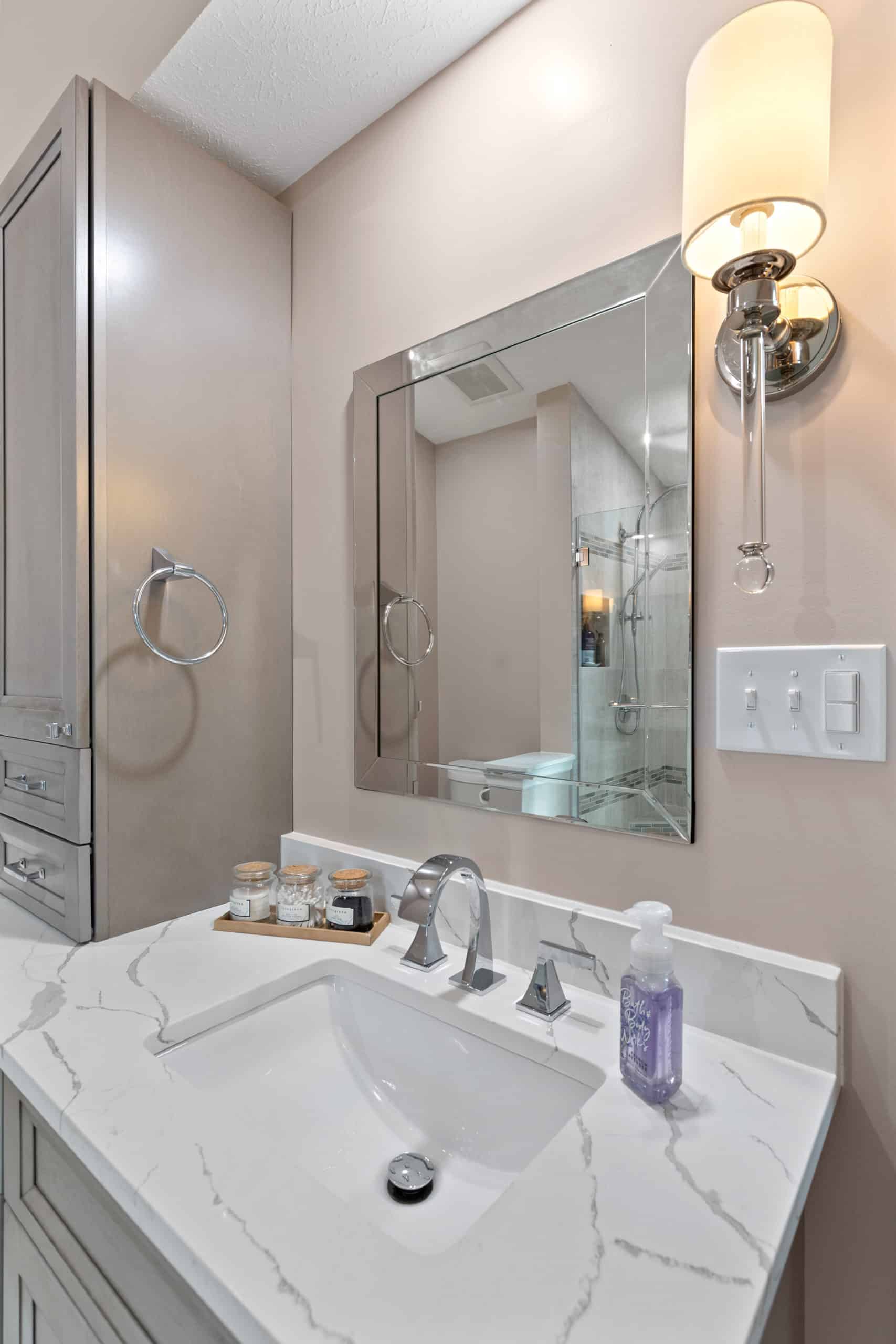 Light pink bathroom with gray vanity, and white countertop