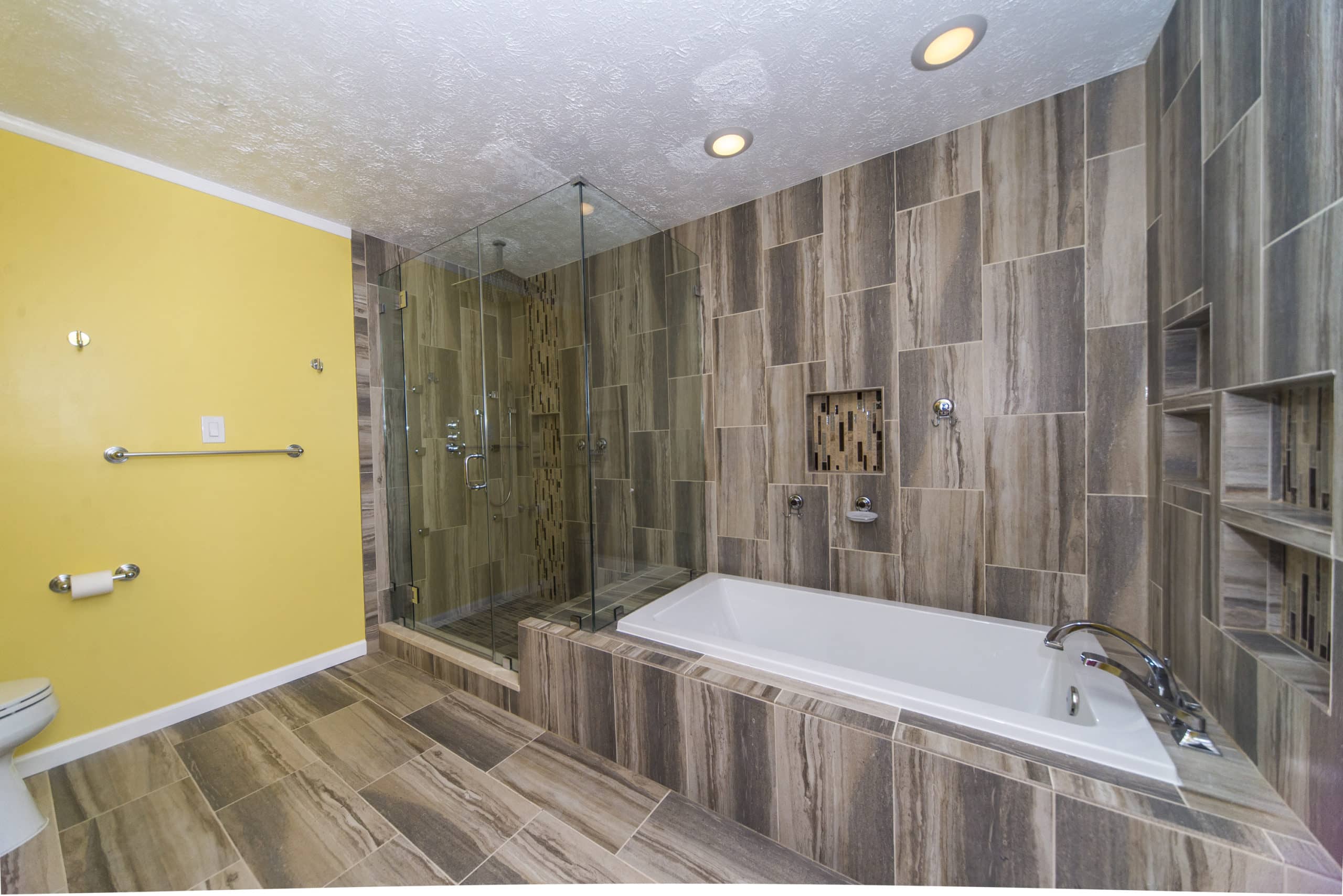 Spacious bathroom with wood colored flooring and wall, on a toilet, bath tub and shower