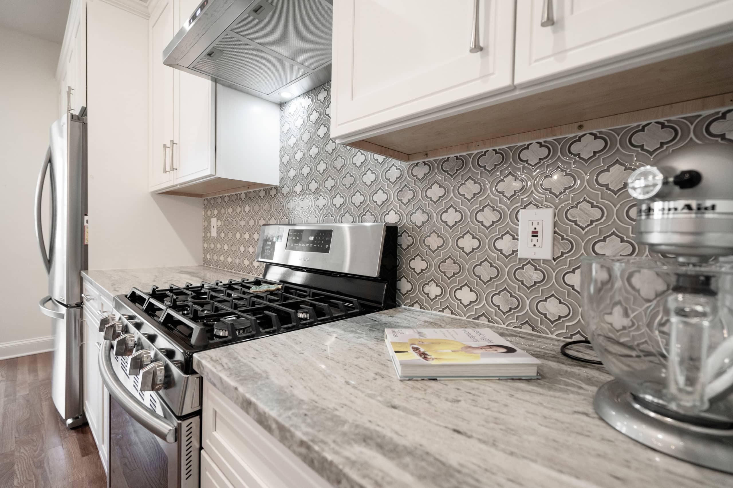 Clean kitchen style with white transitional kitchen cabinets, gray backsplash, and gray countertop