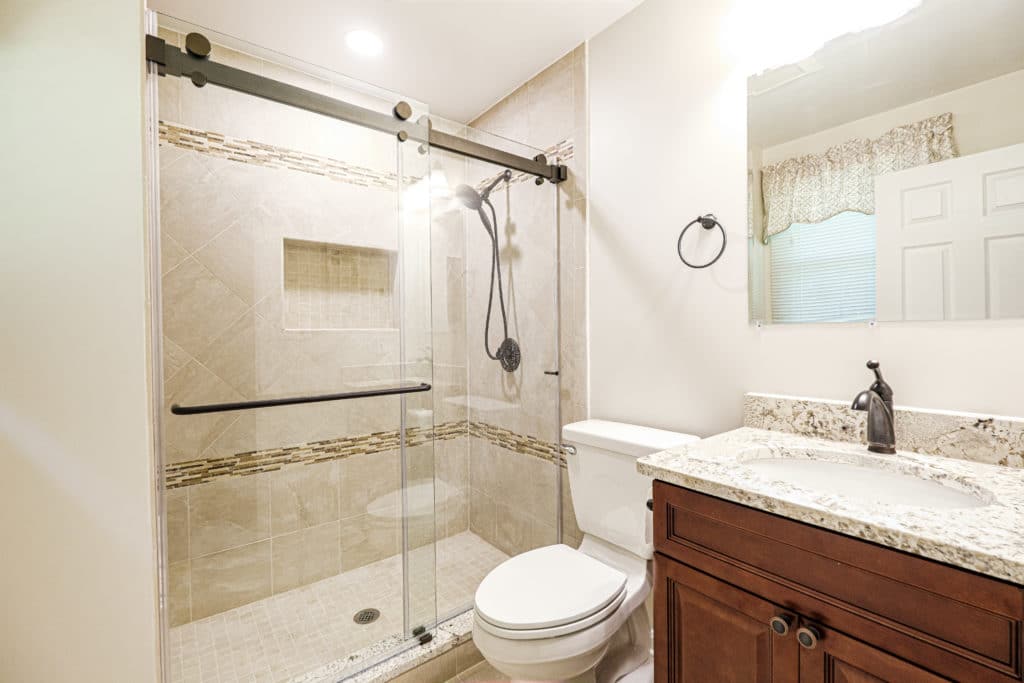 Clean, sleek bathroom with brown vanity, toilet, and a shower