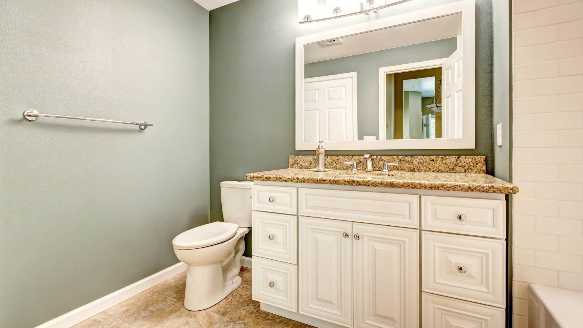 Elegant bathroom with white cabinets, granite countertop, and toilet