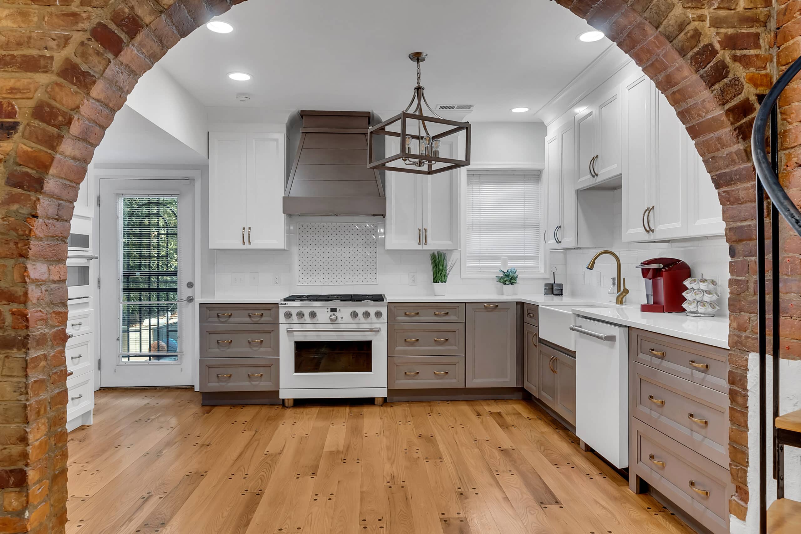 Spacious kitchen with white and grey cabinets, wood flooring, and white countertop