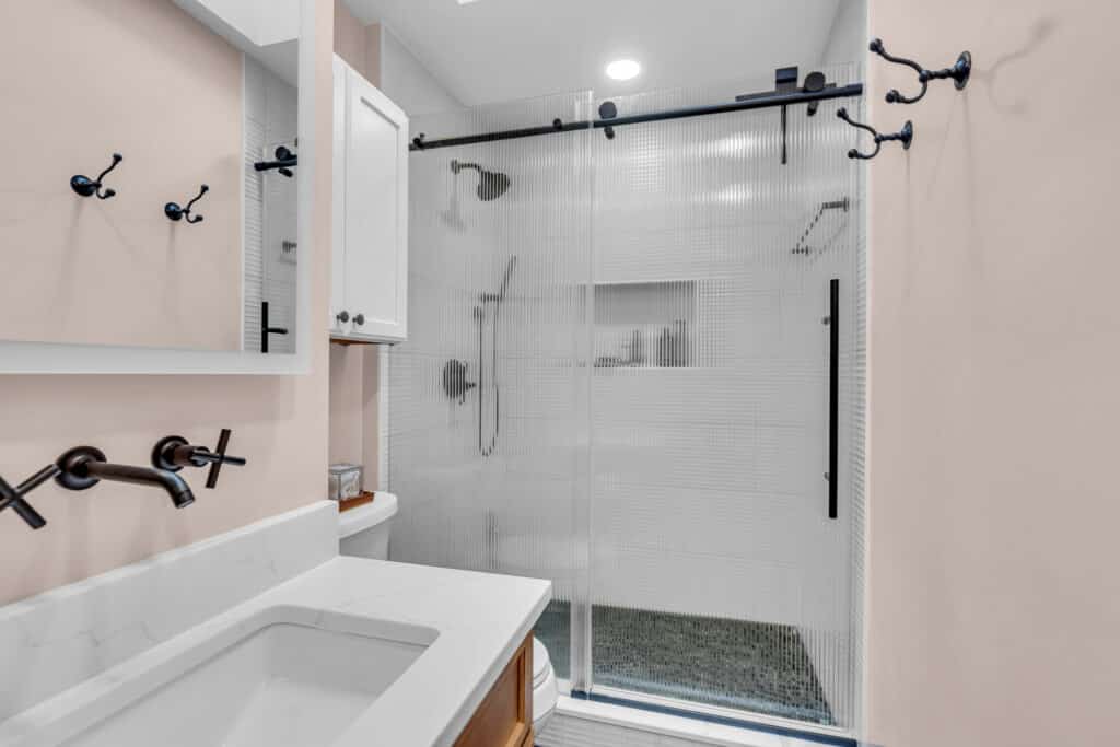 Beige bathroom with brown vanity, black hardware, and a shower