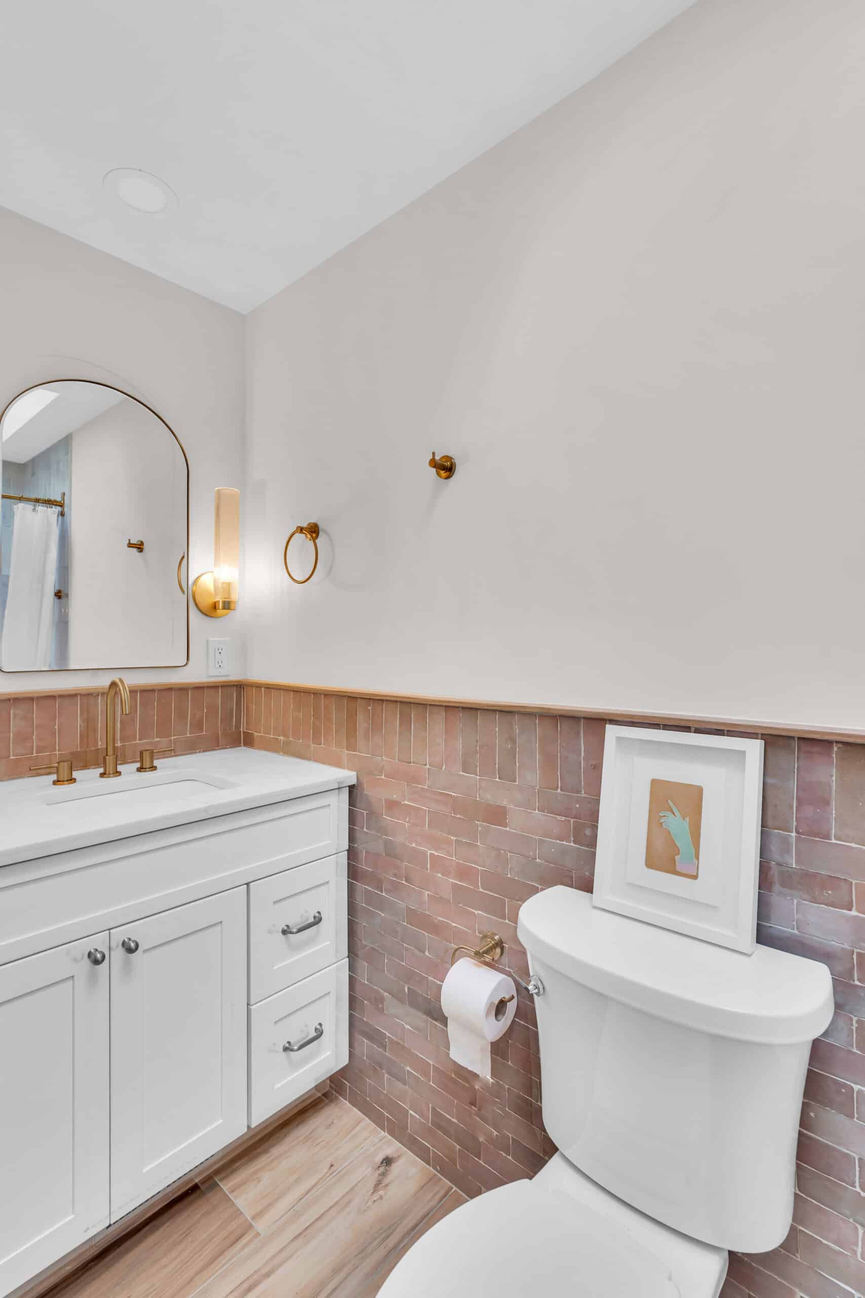 White bathroom vanity and toilet with brown tile surround