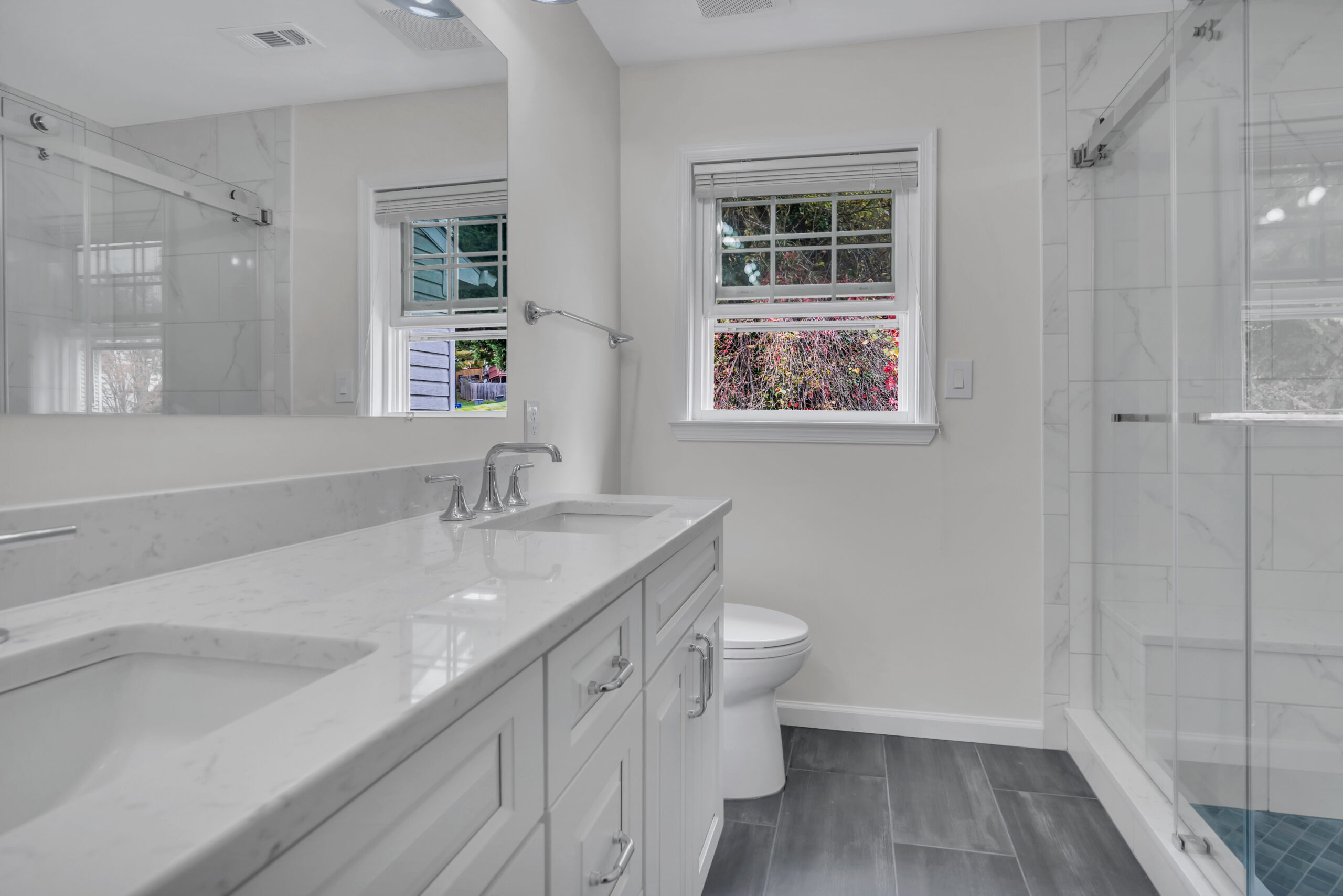 White bathroom style with white cabinets and countertops, toilet, and a shower