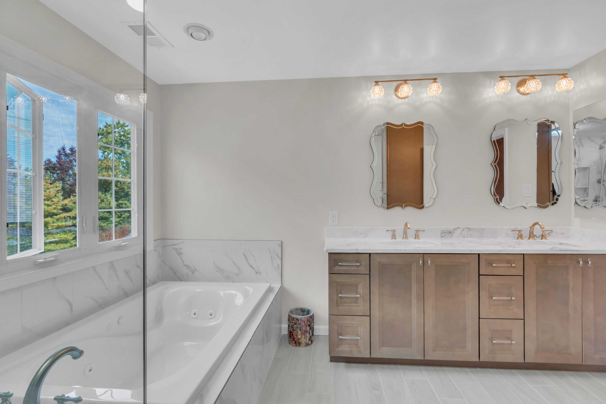 Spacious, luxury bathroom style with brown cabinets, bath tub and a shower