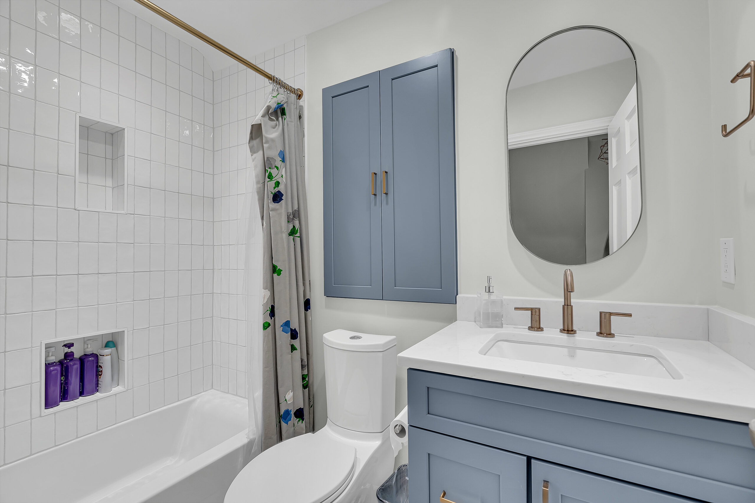 Small bathroom style with light grey vanity, toilet, and a bath tub
