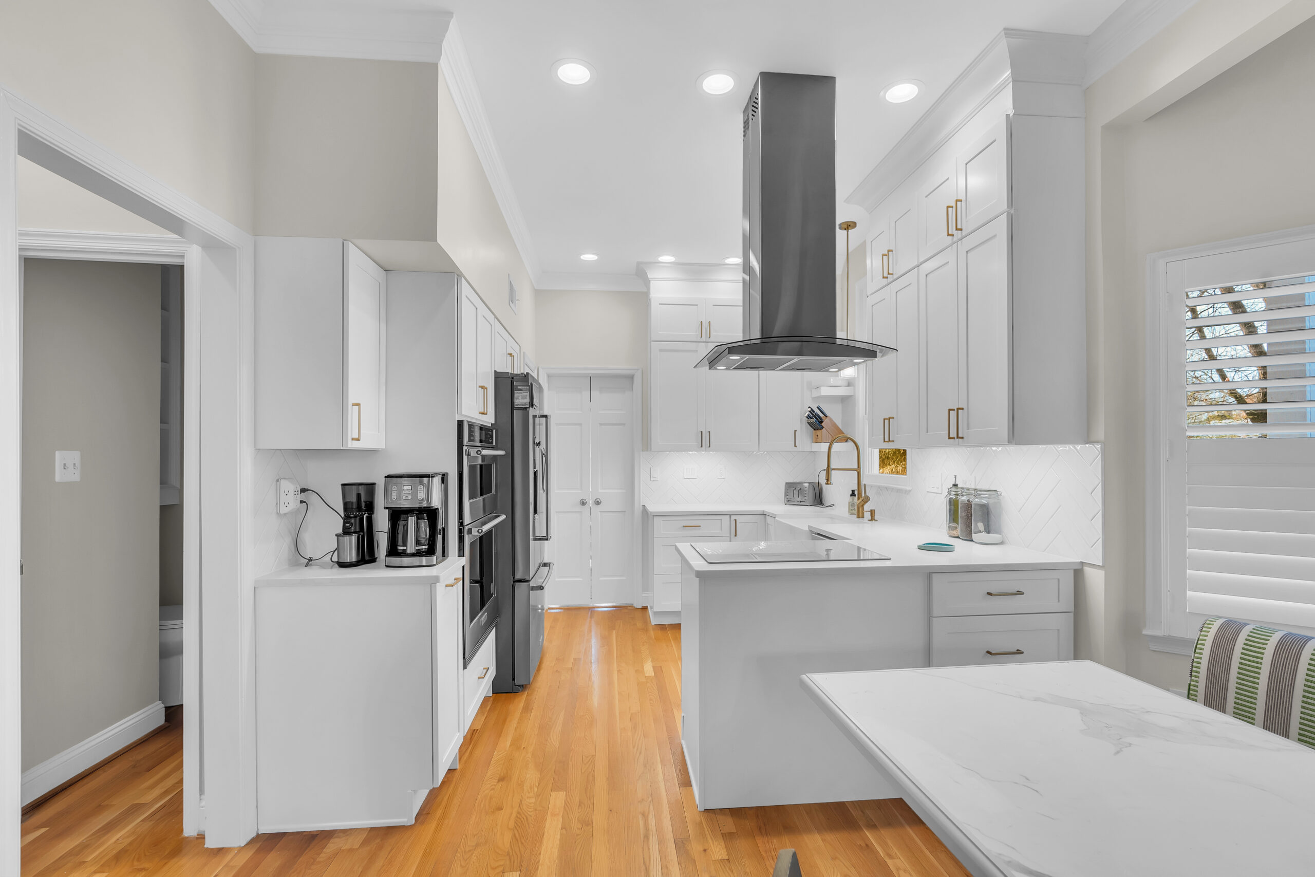 White kitchen design with shaker cabinets and wood flooring