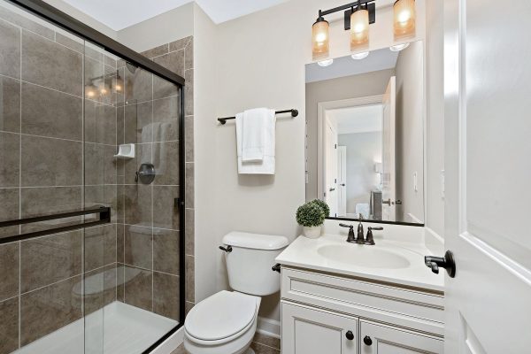 Elegant bathroom with white cabinets, toilet, and shower